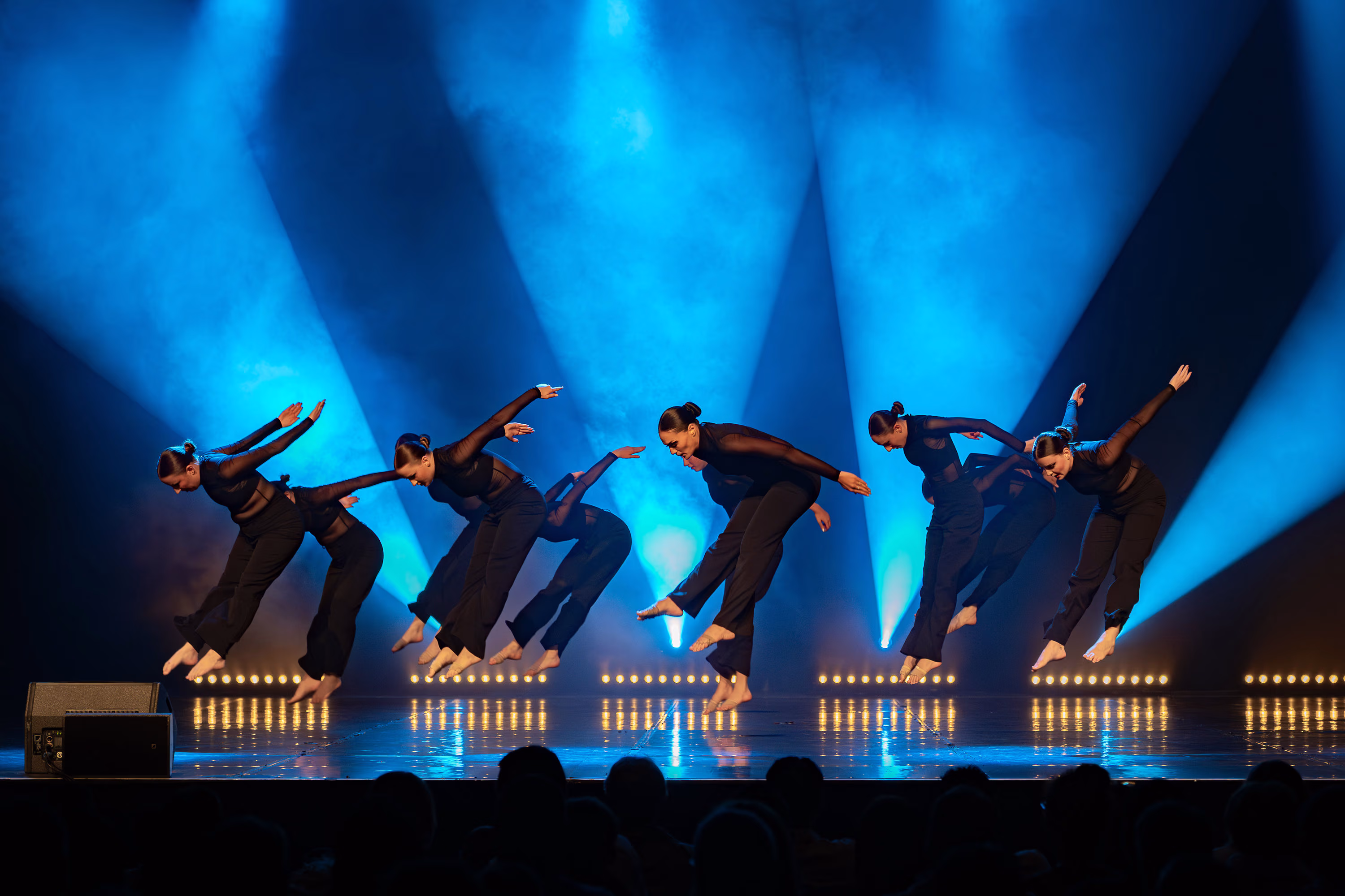 Groupe de danseuses du Studio A réalisant un saut sur scène.